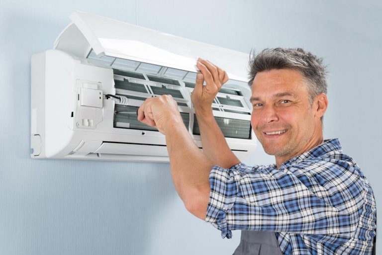 Tehnician HVAC verificând unitatea exterioară a unei pompe de căldură aer-aer